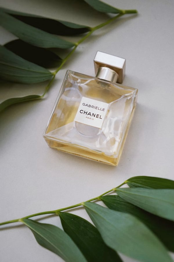 Gabrielle Essence Eau De Parfum bottle on a flat surface with green leaves in the background